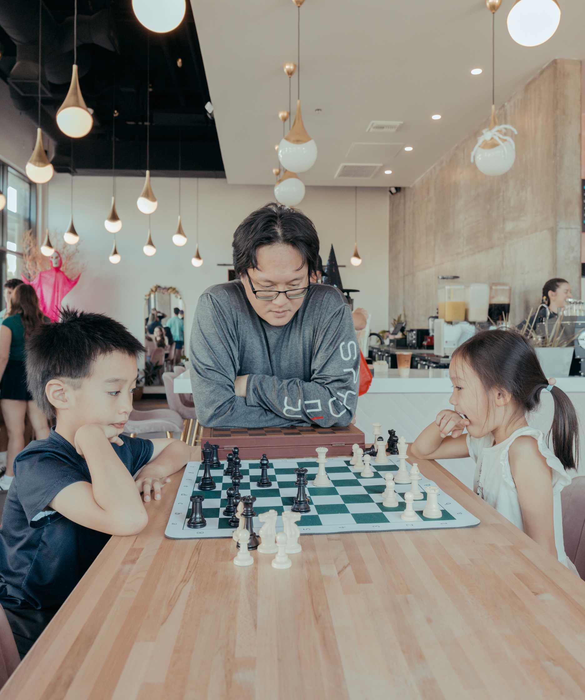 Man watching son and daughter play chess