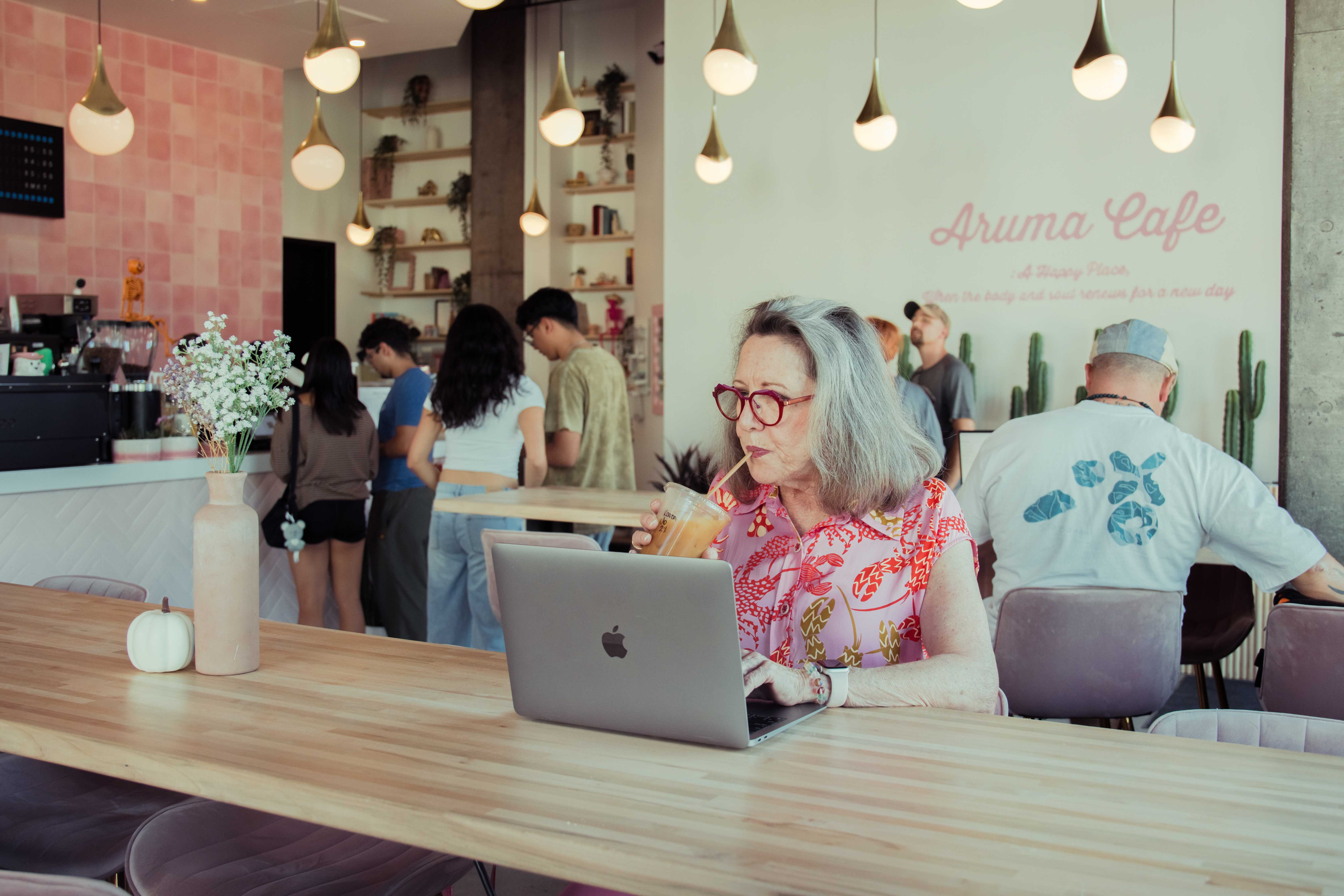 Woman sipping iced coffee at laptop